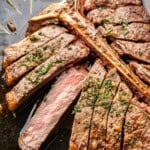 A close up view of a sliced t-bone steak on the bone.