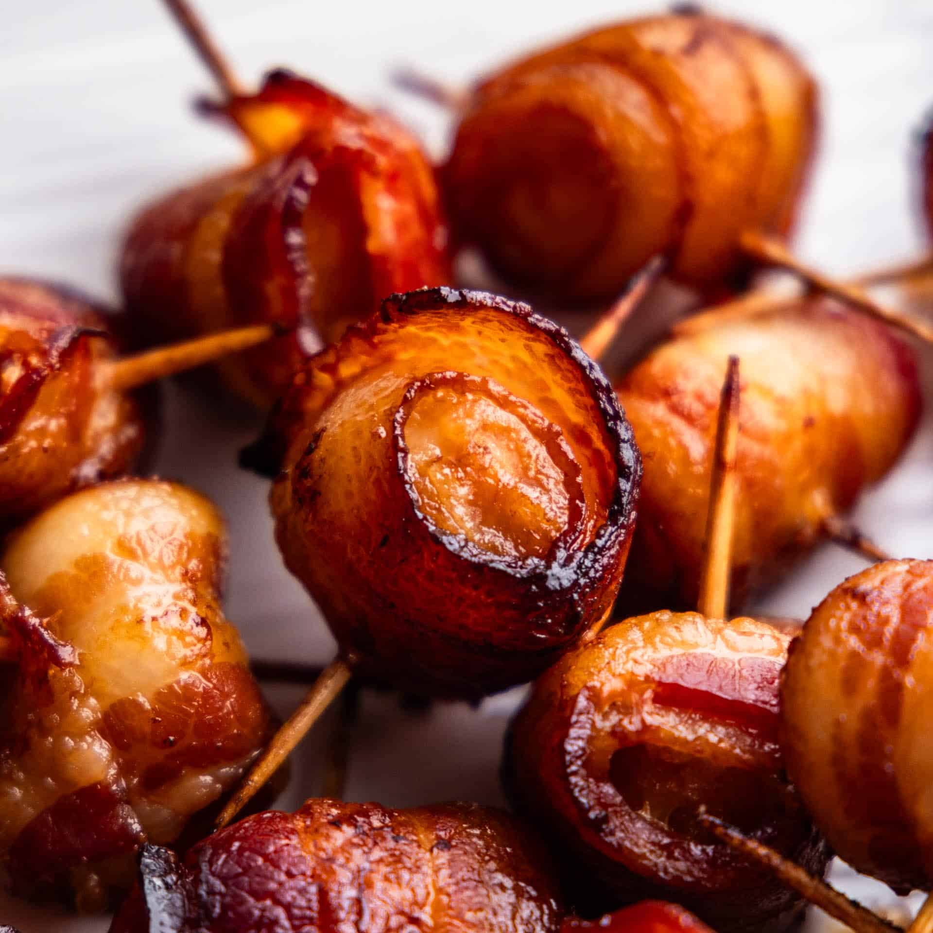 A close up view of a pile of bacon wrapped water chestnuts.