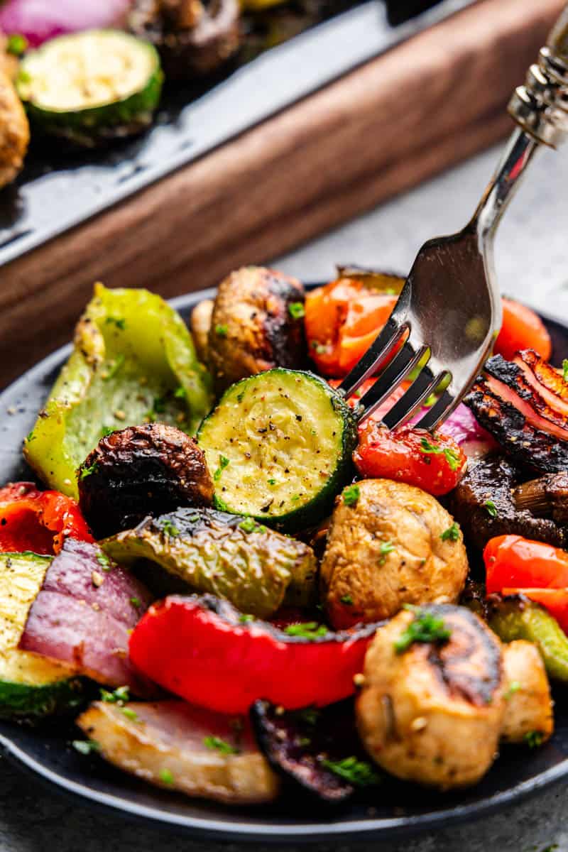 A plate of grilled vegetables with a fork.