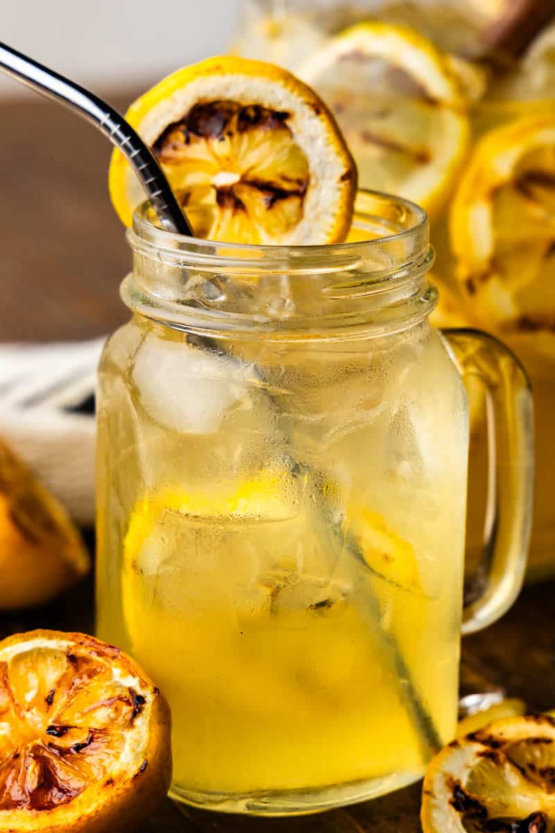 A glass of grilled lemonade with a straw.
