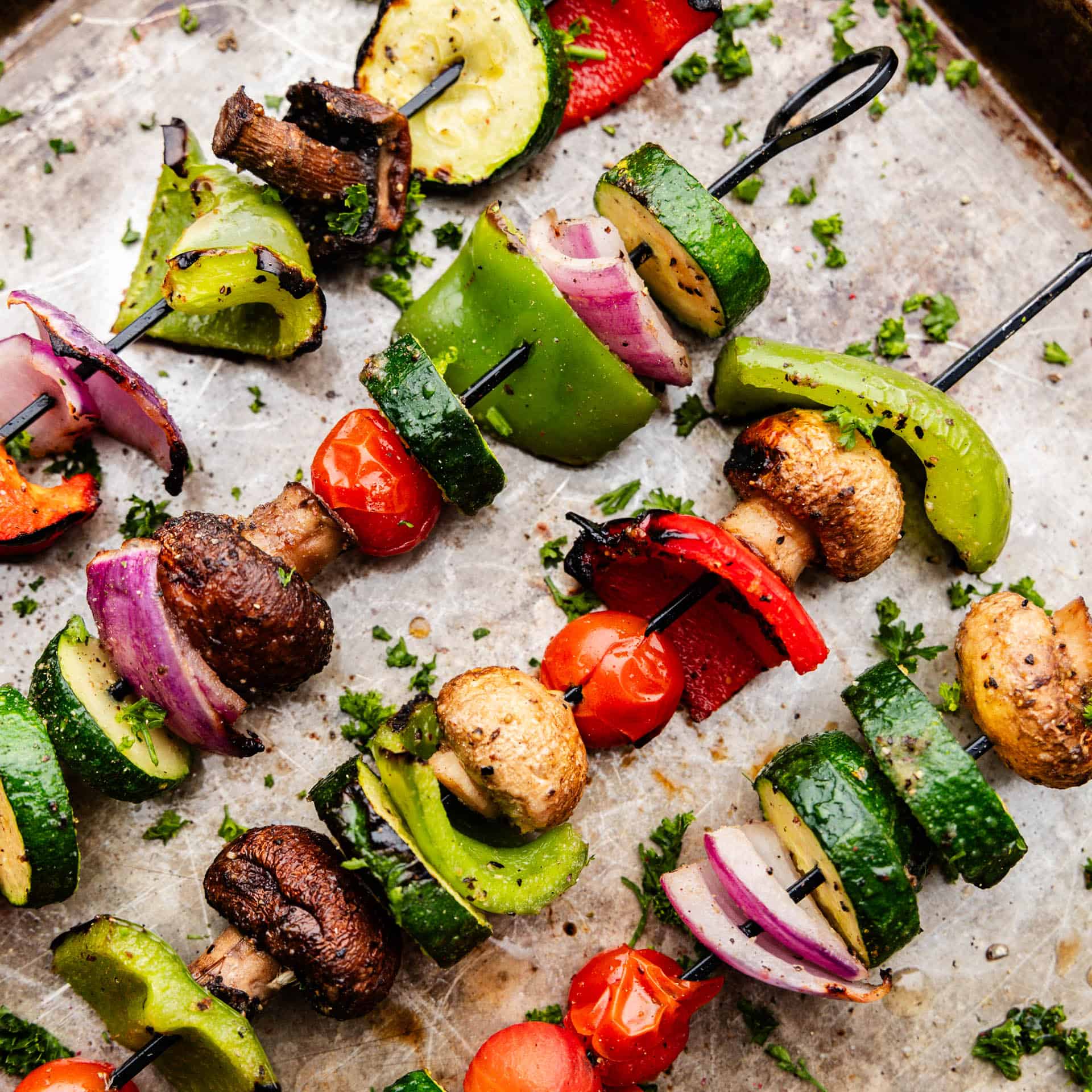 Four grilled vegetable kabobs laying next to each other.