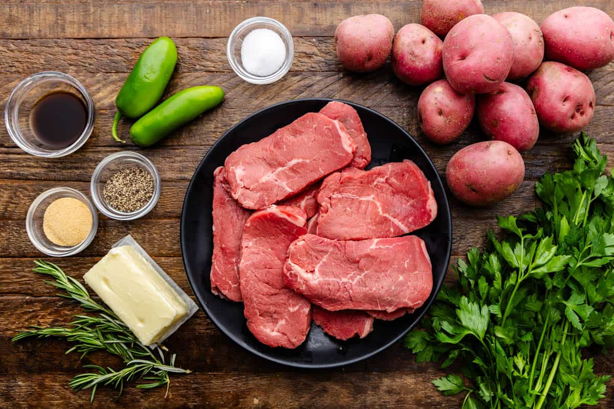 The ingredients for steak and potatoes laid out on a table. 