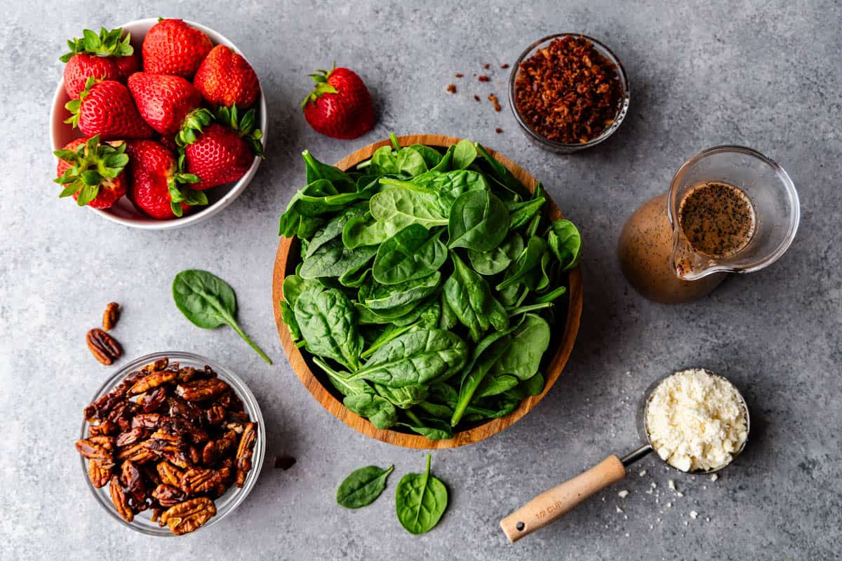 Ingredients for a strawberry spinach salad laid out on a table.