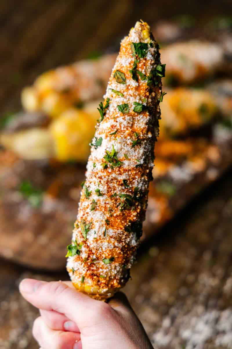 An ear of Mexican Street corn with other pieces in the background.