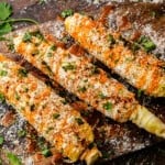 Delicious Mexican street corn laid out on a wooden tray.