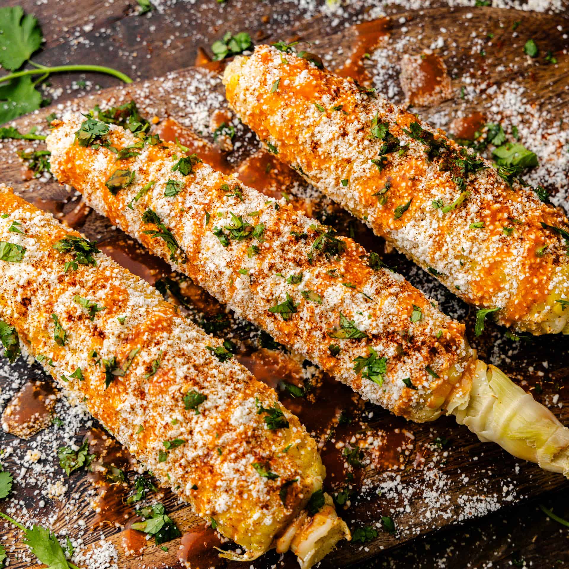 Delicious Mexican street corn laid out on a wooden tray.