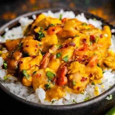 A bowl of white rice topped with coconut curry chicken.