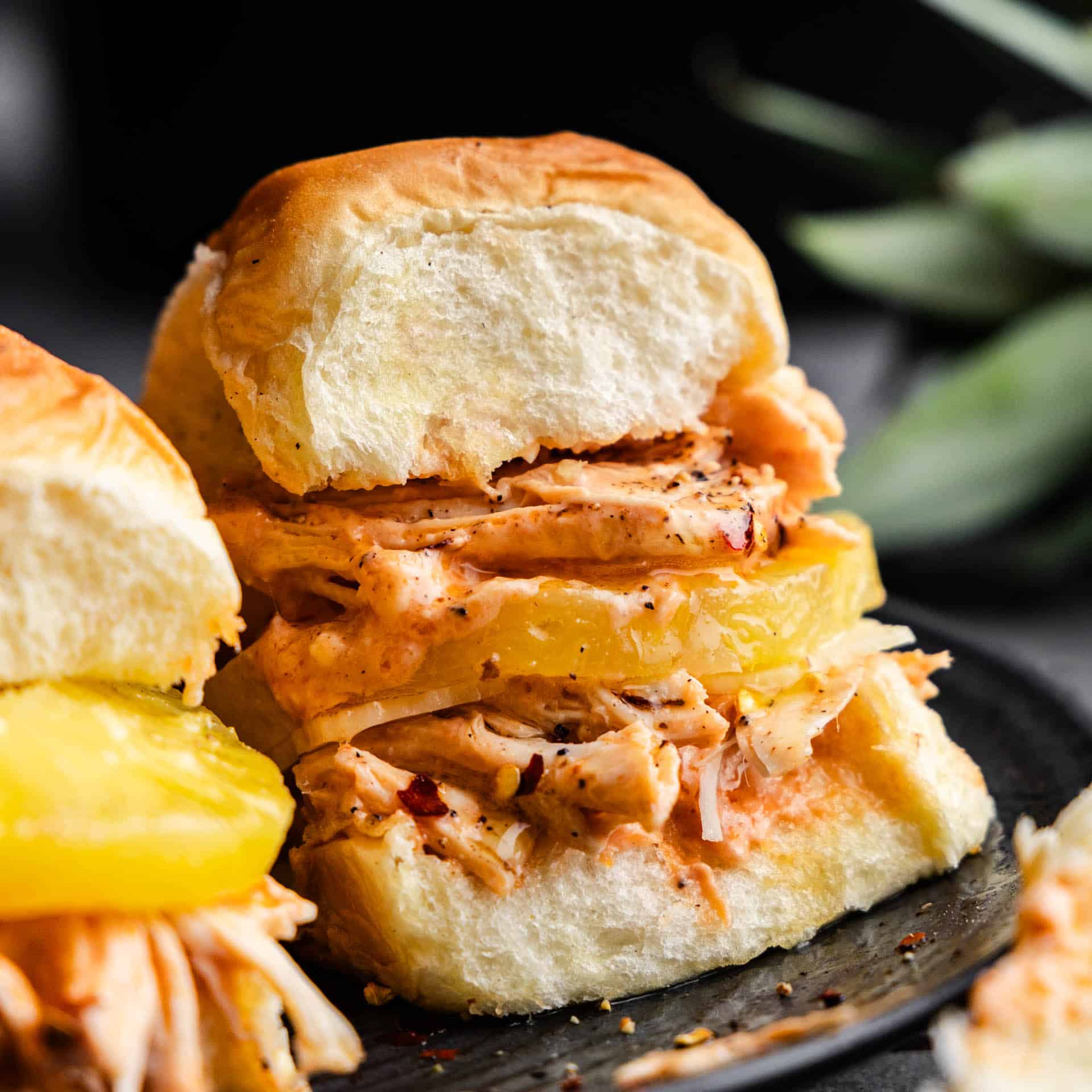 A close up view of a cream cheese chicken slider with pineapple.