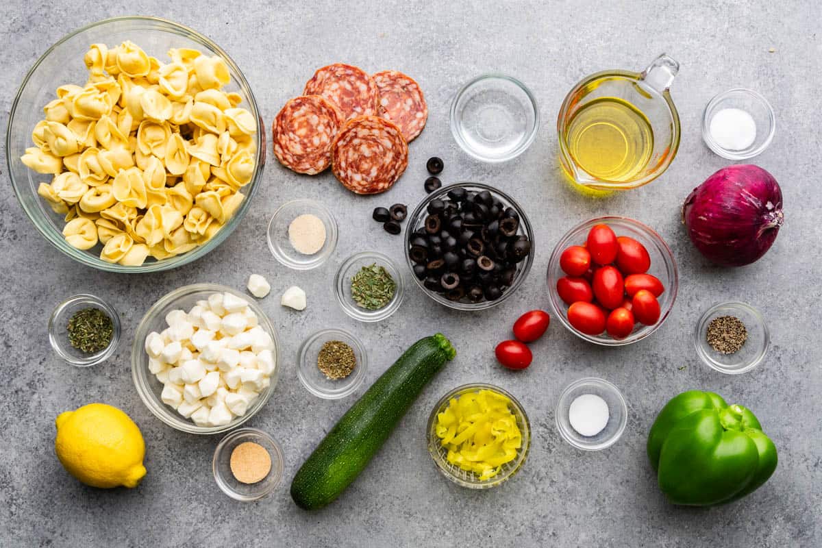 The ingredients for tortellini pasta salad are laid out on a table.