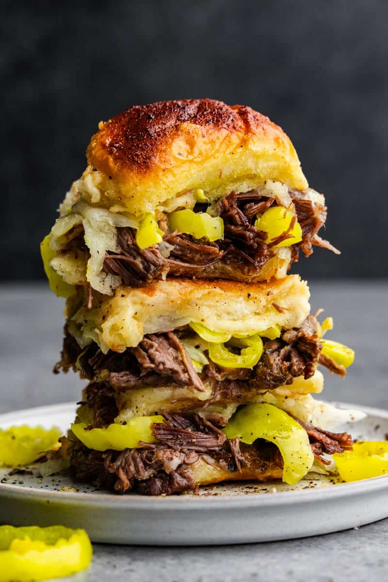 A stack of 3 Mississippi Pot Roast sliders with peppers and cheese.