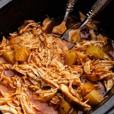 A close up view into a slow cooker full of Hawaiian BBQ chicken.
