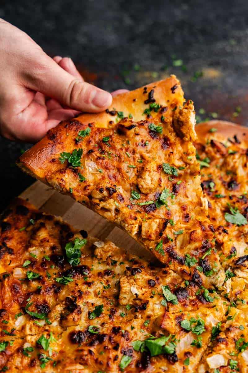 A close up of a slice of chicken tikka masala chicken being lifted and pulled from the whole pie.