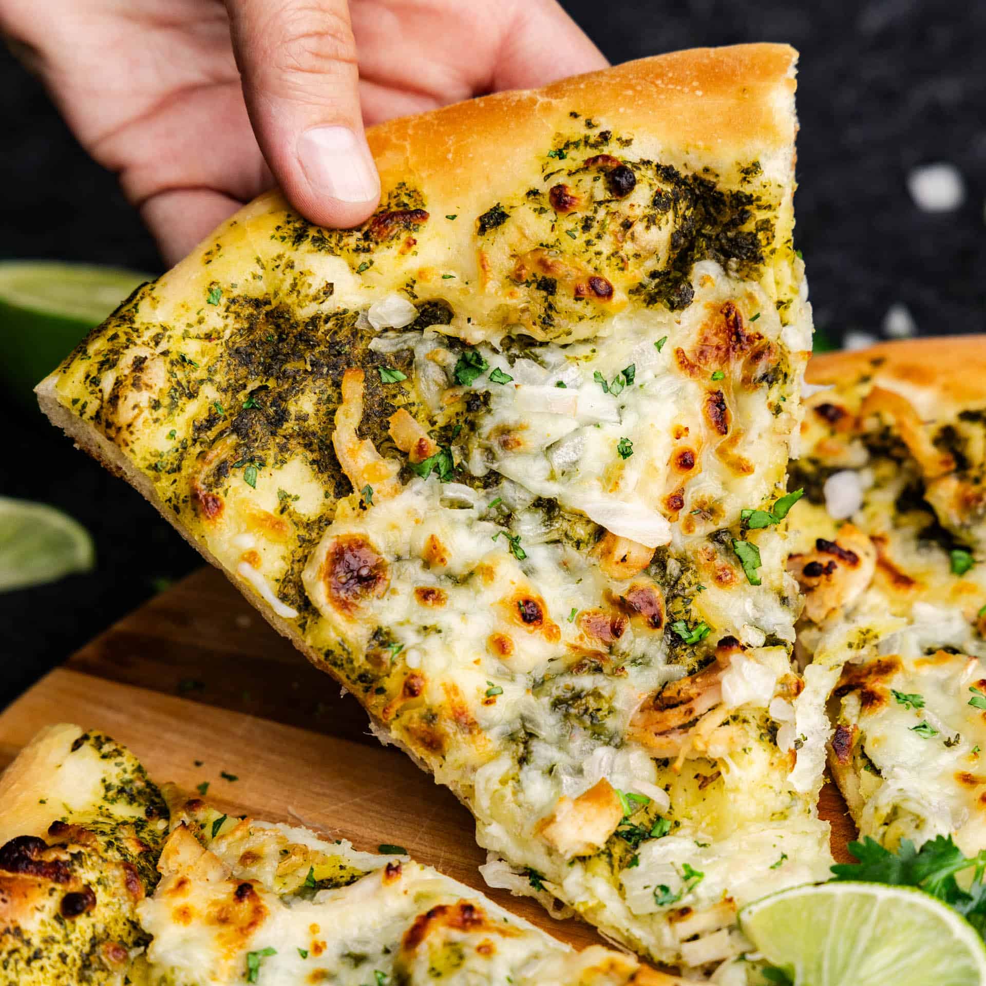 A slice of cilantro lime pizza being pulled from the whole.