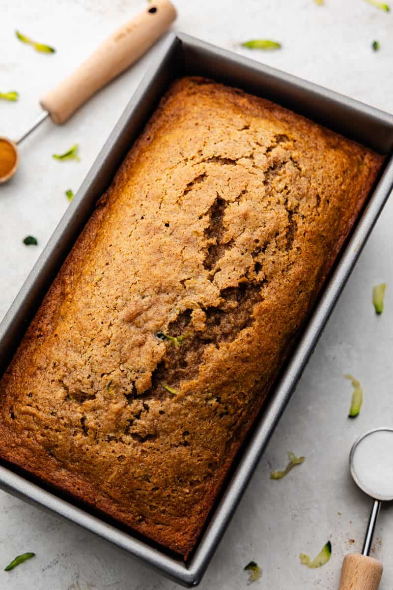 A baked loaf of zucchini bread still in the loaf pan.