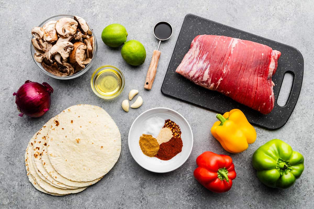 An overhead view of raw and fresh ingredients to make steak fajitas.