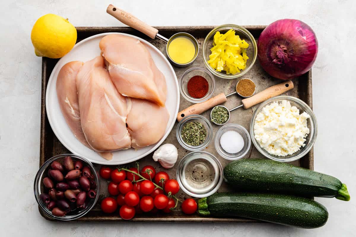 An overhead view of the ingredients needed to make sheet pan Greek chicken and veggies.