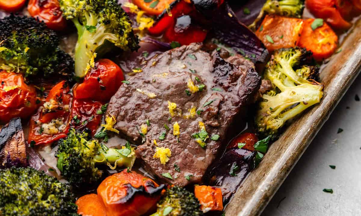 A close up overhead view of a sheet pan of Italian steak and veggies.