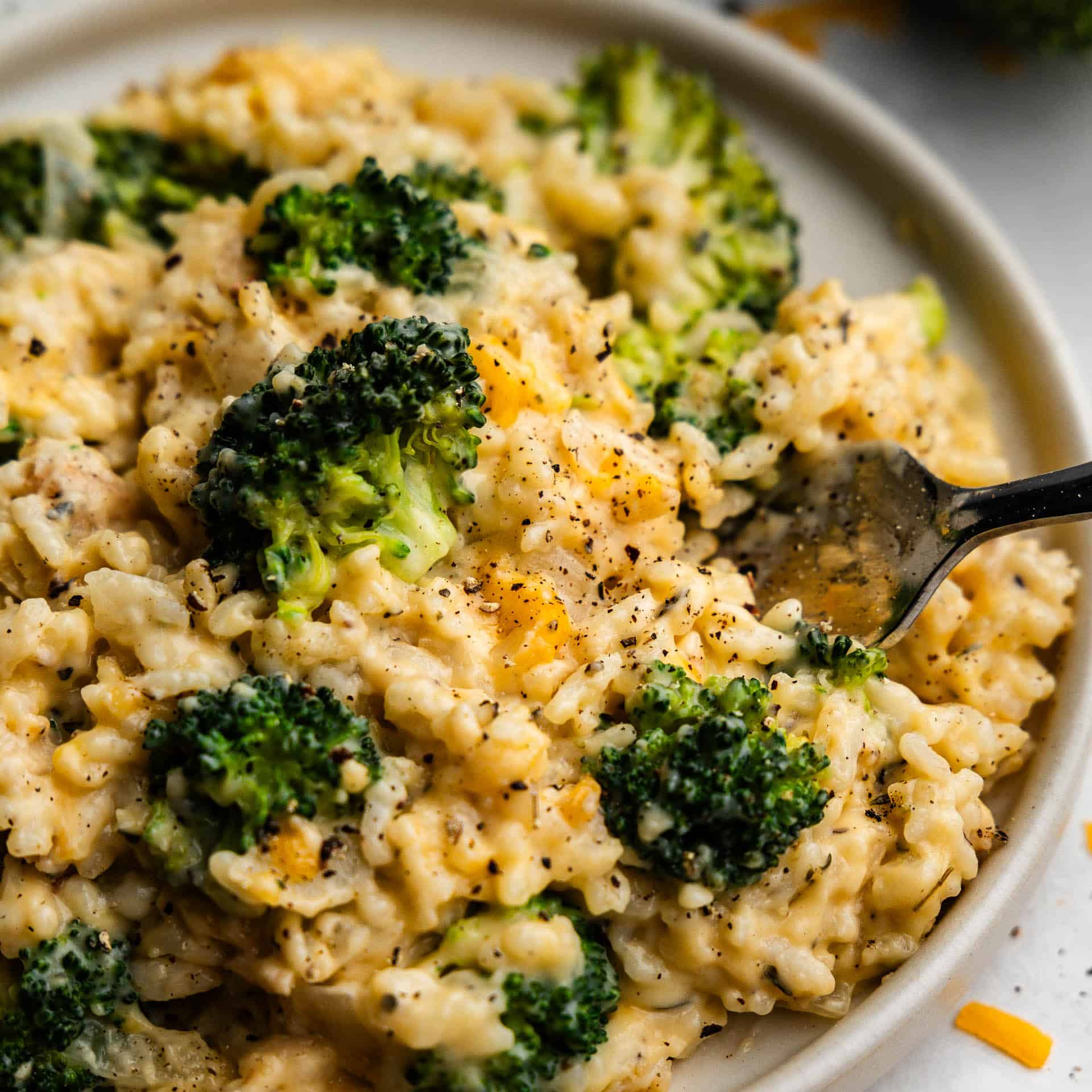 An overhead view of a plate of chicken broccoli and rice, with a fork placed into it.