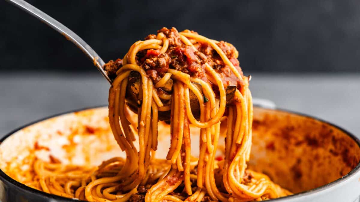 A large serving of saucy spaghetti being lifted from a pot.