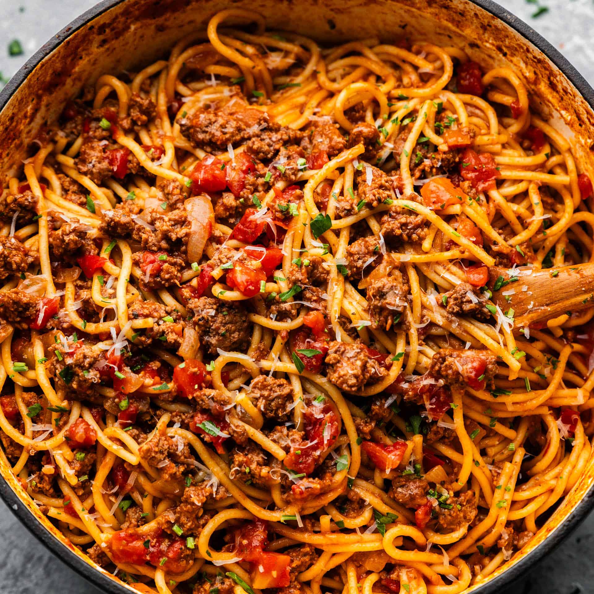 A top view of a pot of spaghetti mixed with a ground beef and tomato sauce.