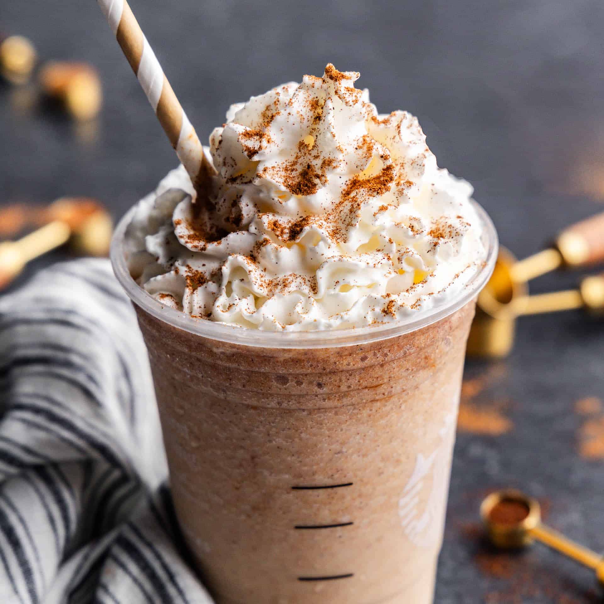 A close up view of a pumpkin spice frappe in a plastic cup.