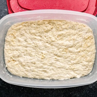 An overhead view of a large container full of refrigerator pizza dough.