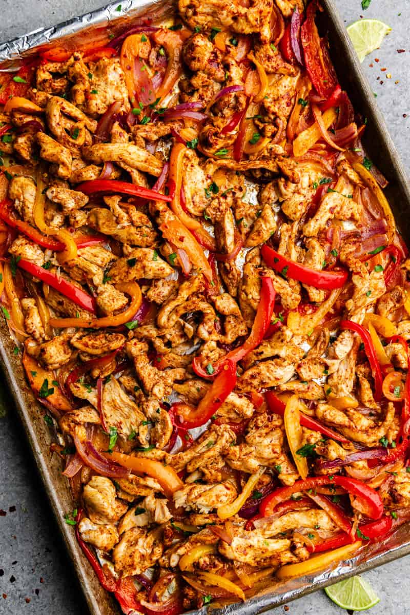 A top view of a sheet pan full of seasoned and cooked chicken fajitas.