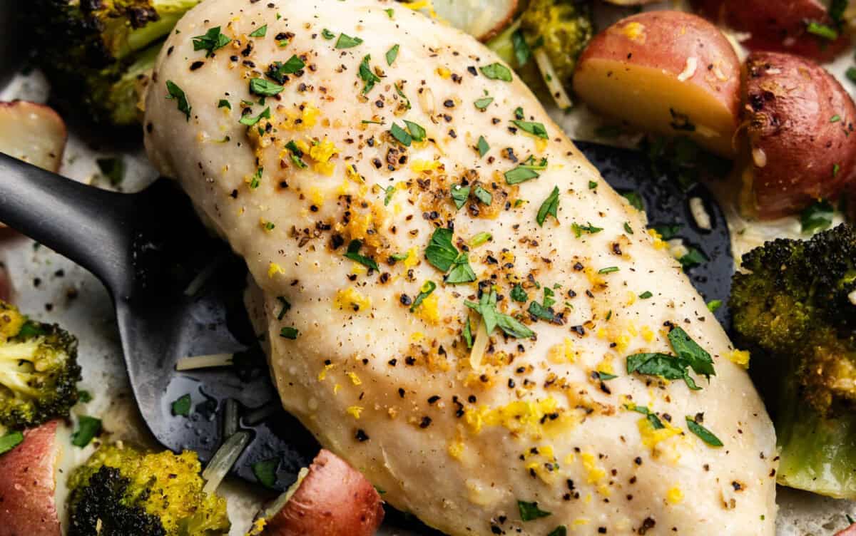 A close up view of sheet pan garlic parmesan chicken and potatoes with broccoli.