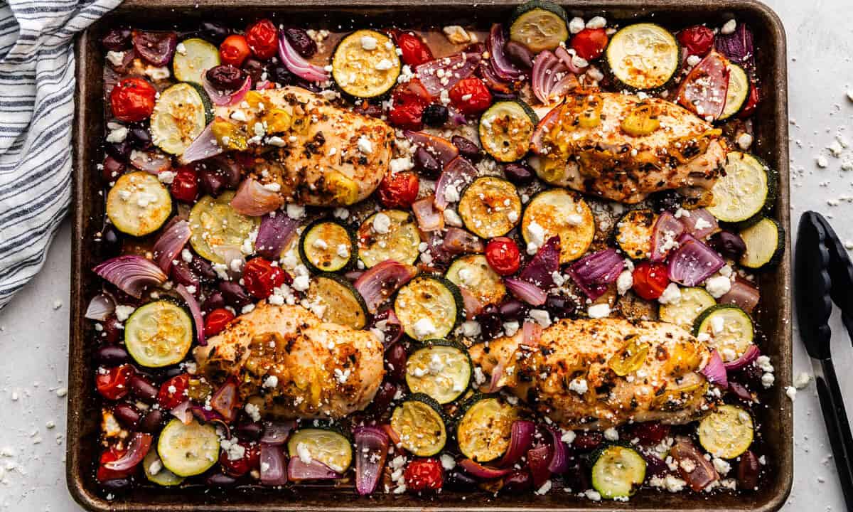 An overhead view of a sheet pan Greek chicken baked with roasted vegetables.