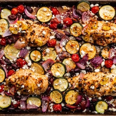 An overhead view of a sheet pan Greek chicken baked with roasted vegetables.