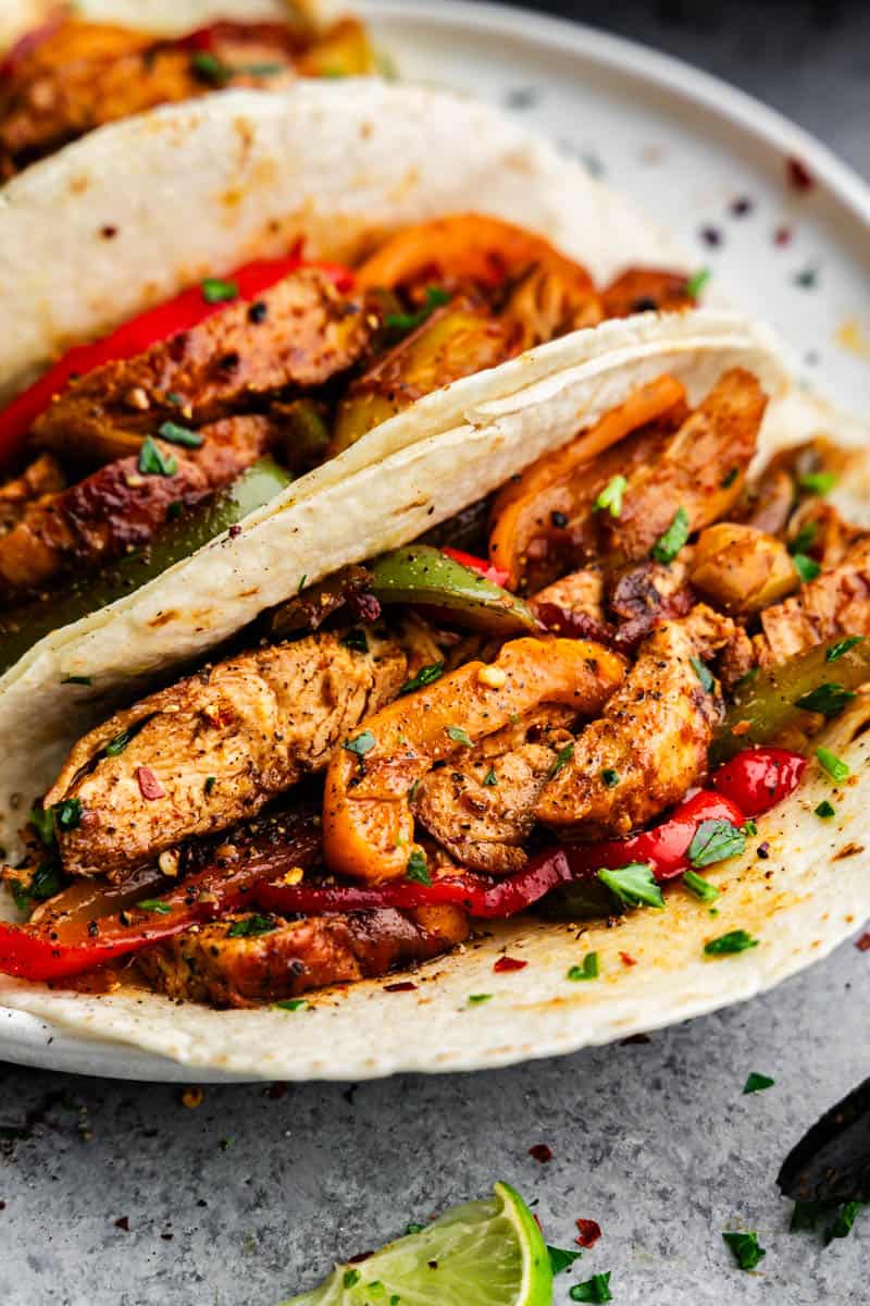 A close up of chicken fajitas loaded into flour tortillas.