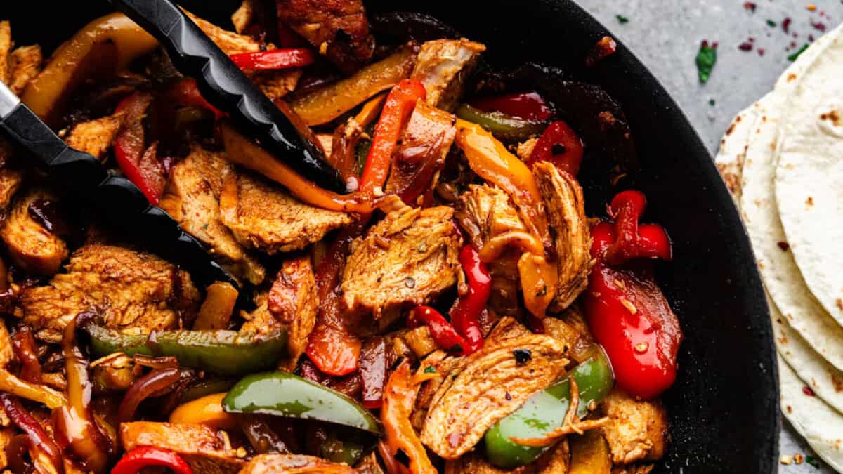 A closeup overhead view of chicken fajitas in a skillet.