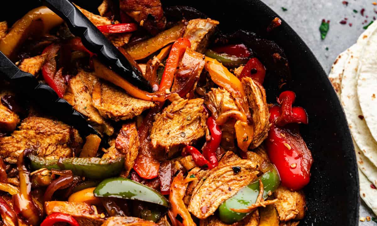 A closeup overhead view of chicken fajitas in a skillet.