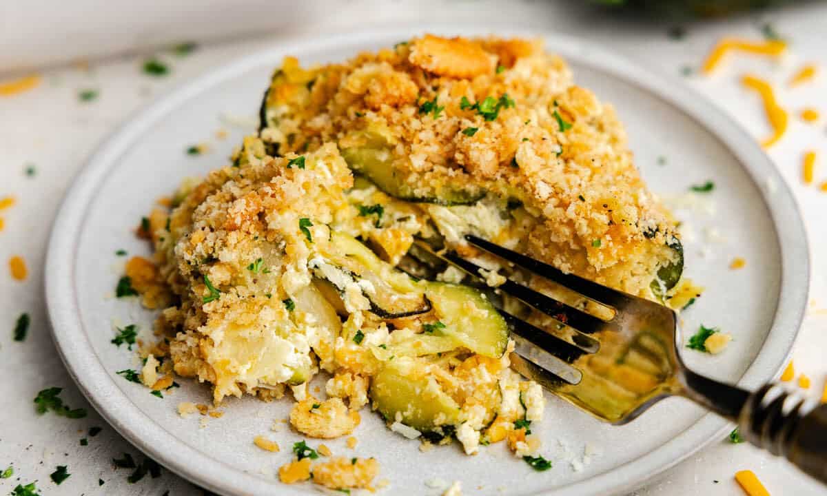 A plate with a serving of zucchini casserole, with a fork sitting on the plate ready for a bite.