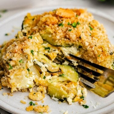 A plate with a serving of zucchini casserole, with a fork sitting on the plate ready for a bite.