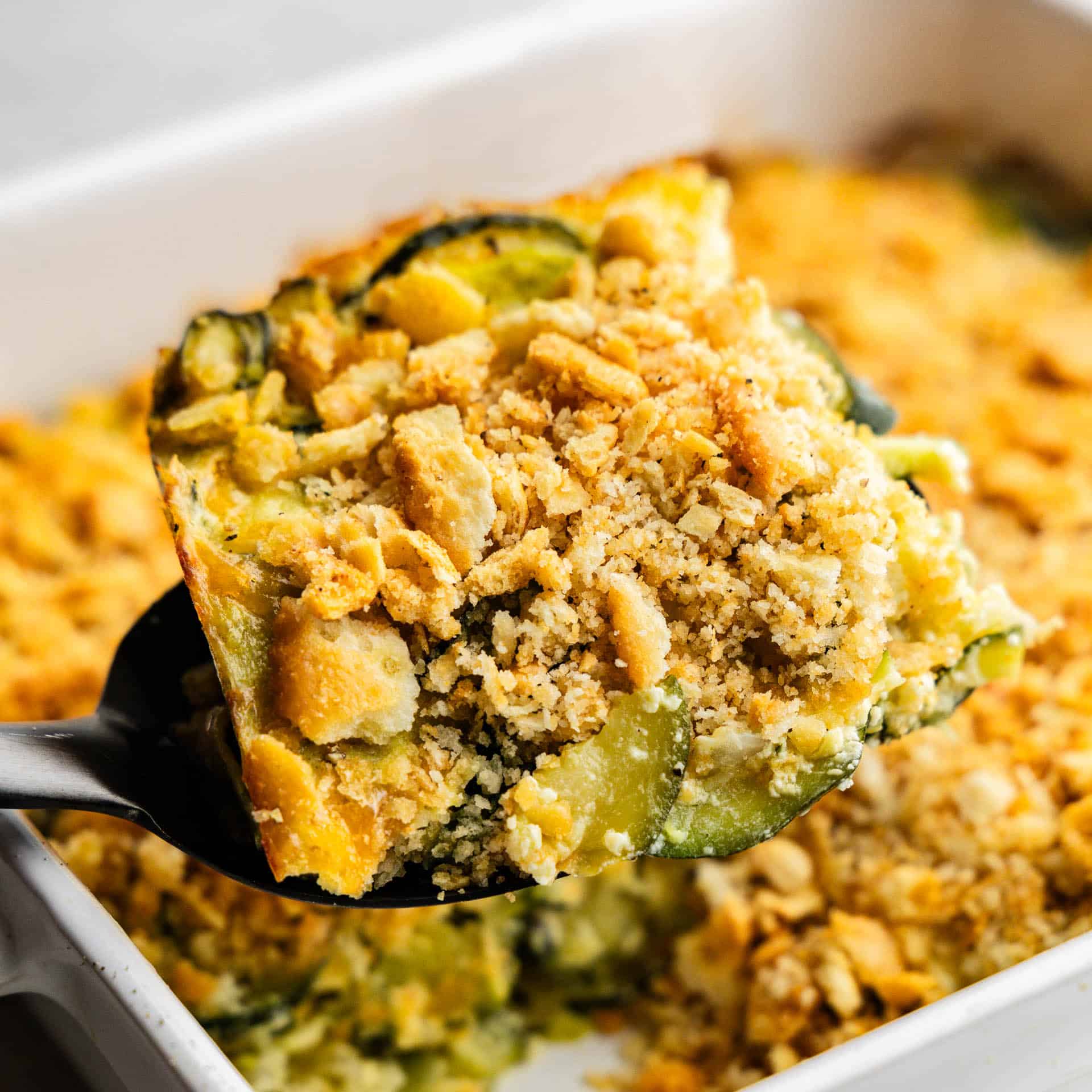 A portion of zucchini casserole being lifted from the dish.