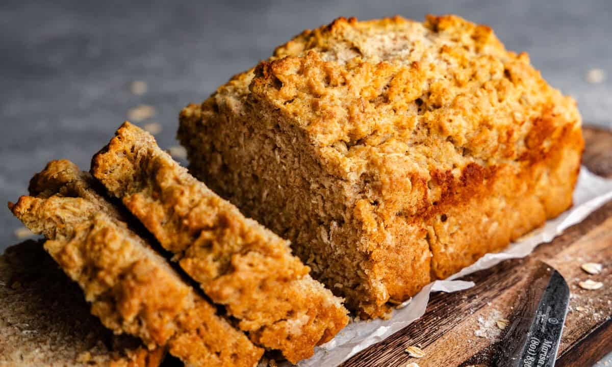 A loaf of beer bread sitting on a wooden cutting board. Two slices have already been cut out.