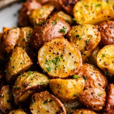 A plate loaded with cut, seasoned and perfectly golden potato chunks.