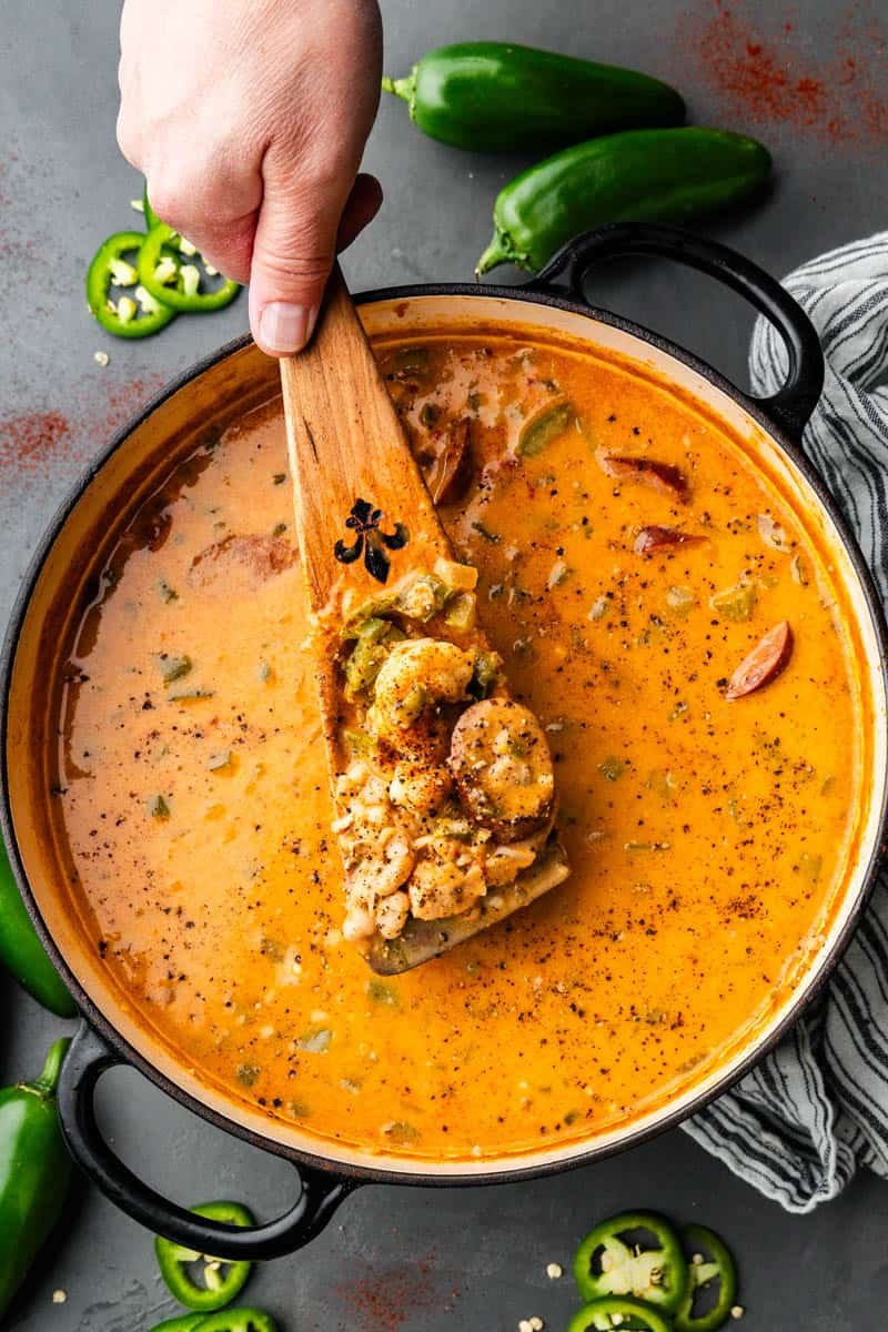 An overhead view of a pot of Cajun white chicken chili with a spoon dishing out a serving.