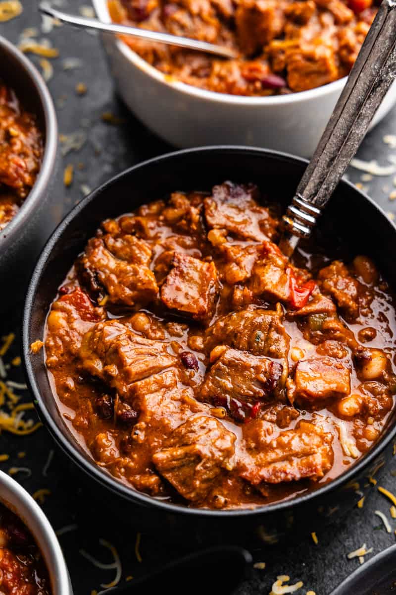 A close-up overhead view of a bowl of chili with a spoon.