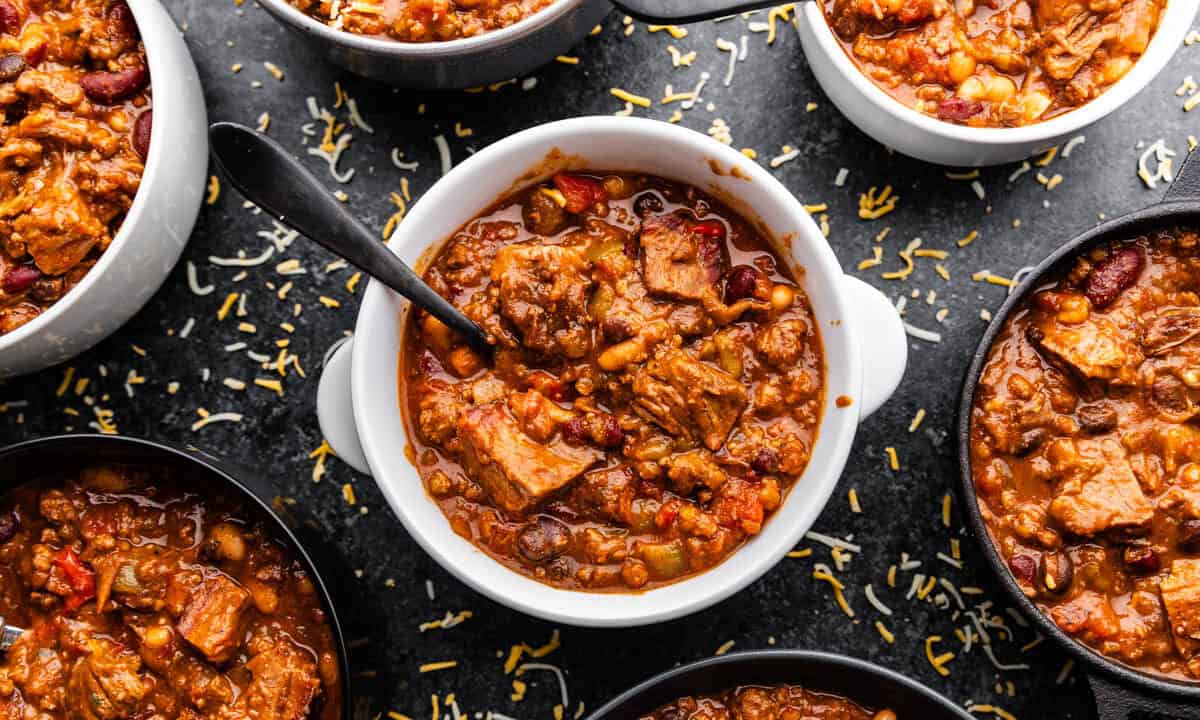 A top view of several bowls filled with chili, with the center bowl having a spoon in it.