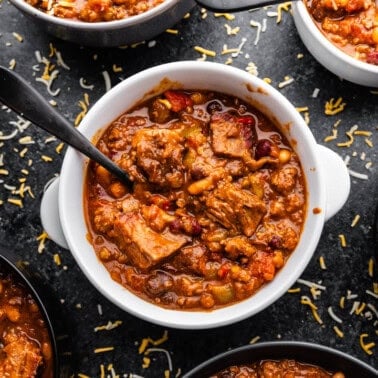 A top view of several bowls filled with chili, with the center bowl having a spoon in it.