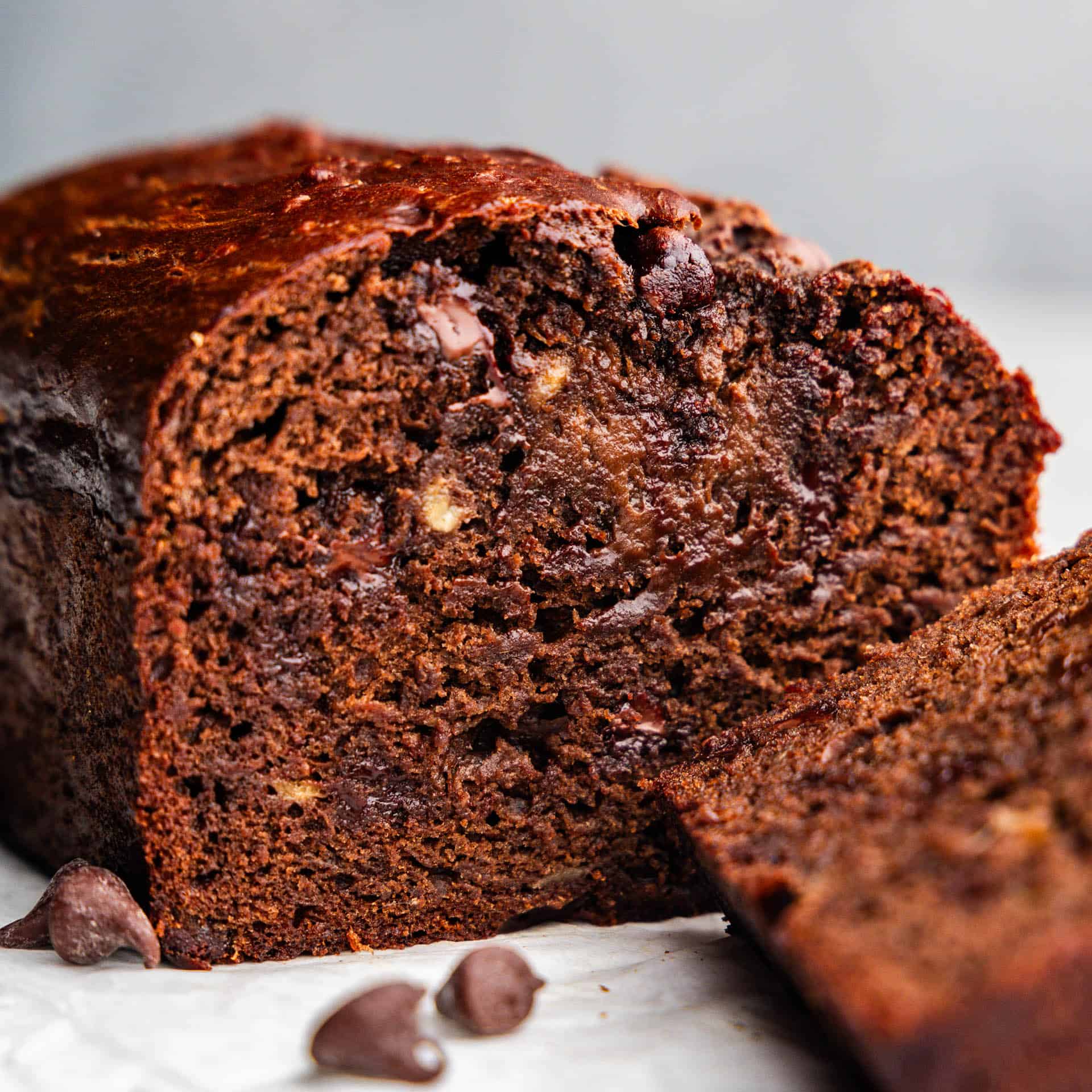 A close up of a loaf of chocolate banana bread with slices cut off.