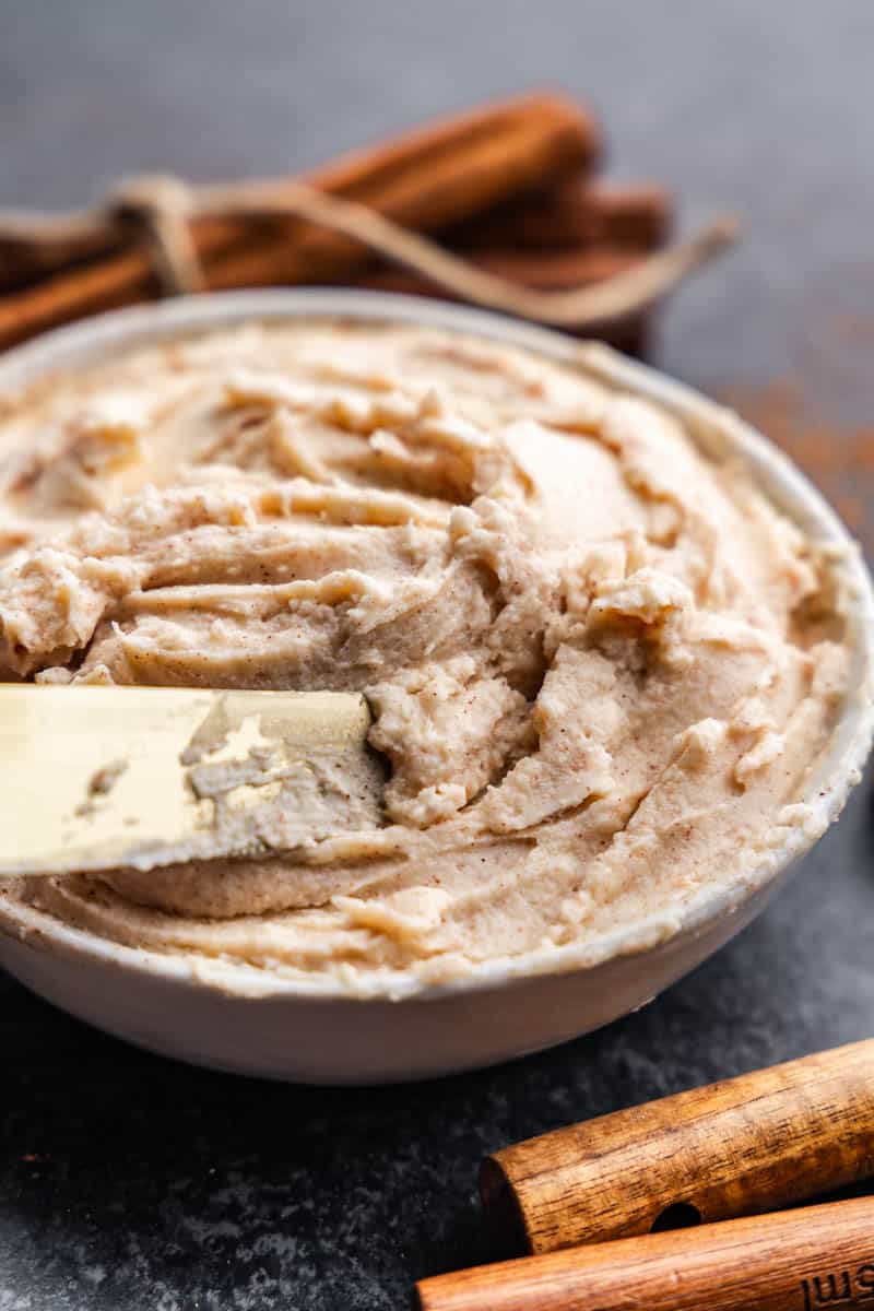 A bowl of cinnamon cream cheese butter with a knife resting in the bowl.