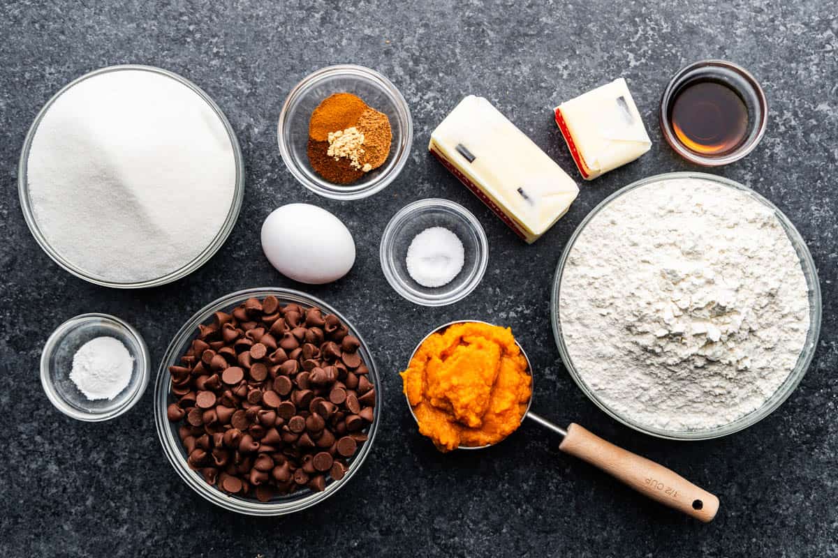 An overhead view of wet and dry ingredients needed to make pumpkin chocolate chip cookies.