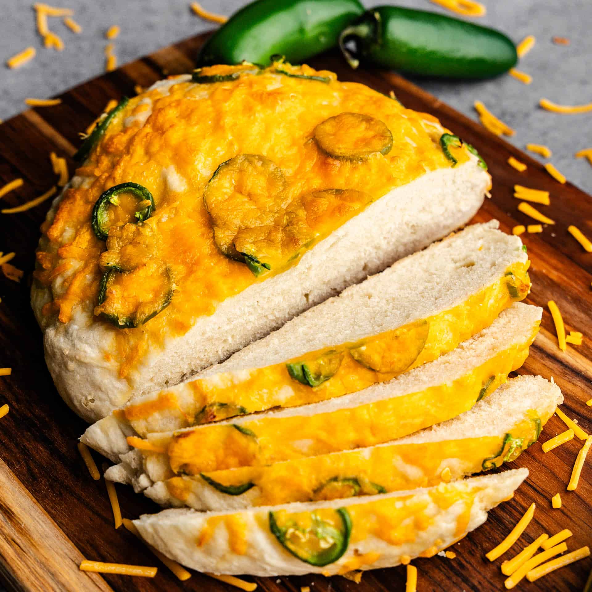 A top view of a half sliced loaf of jalapeno cheese bread on a cutting board.