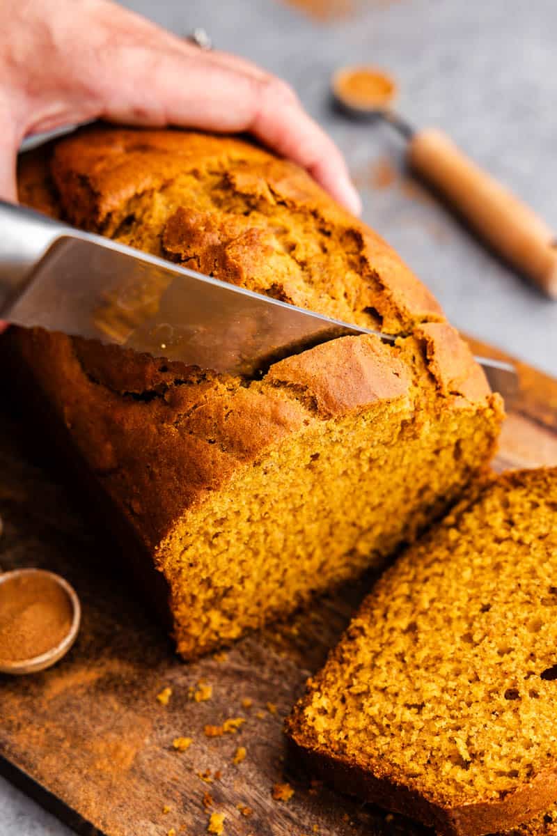 A close-up view of slicing pumpkin bread on a cutting board