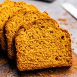 A close up view of 3 slices of pumpkin bread on a cutting board.