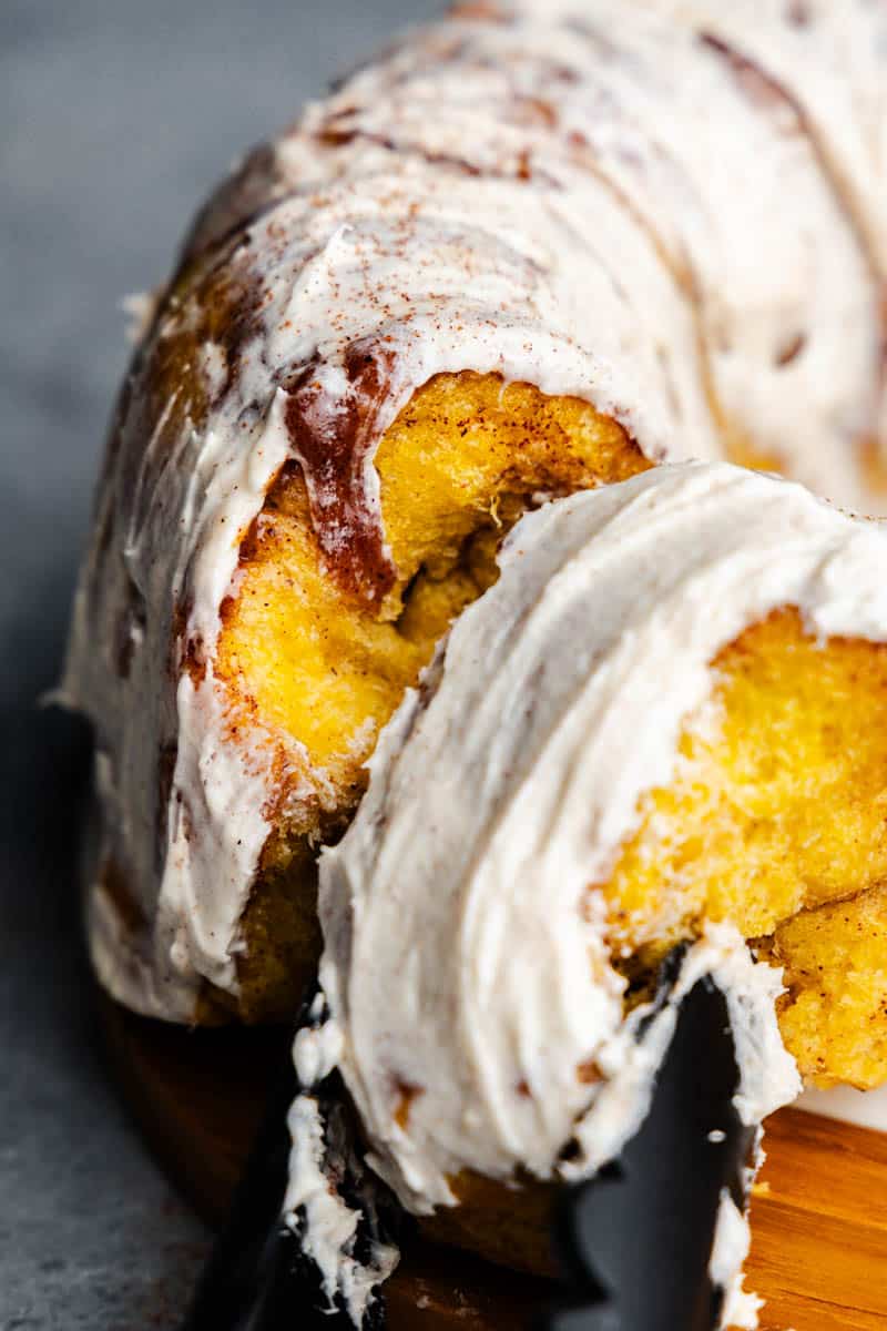 A close up of tongs removing a slice of pumpkin pull apart monkey bread.