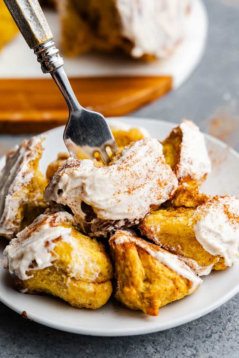 A plate filled with pumpkin pull apart monkey bread, with a fork spearing into the pile for a bite.